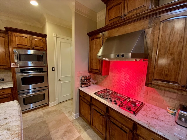 kitchen with appliances with stainless steel finishes, tasteful backsplash, wall chimney range hood, light stone counters, and light tile floors