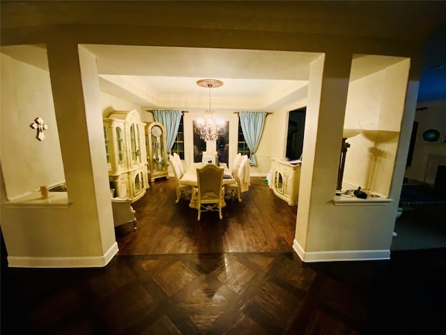 dining area with hardwood / wood-style floors, a notable chandelier, and a raised ceiling