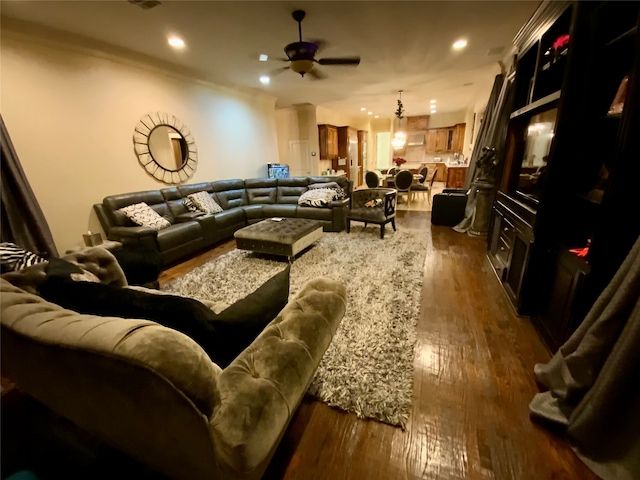 living room featuring wood-type flooring, ceiling fan, and crown molding