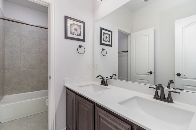 full bathroom with tile flooring, toilet, dual vanity, and tiled shower / bath combo