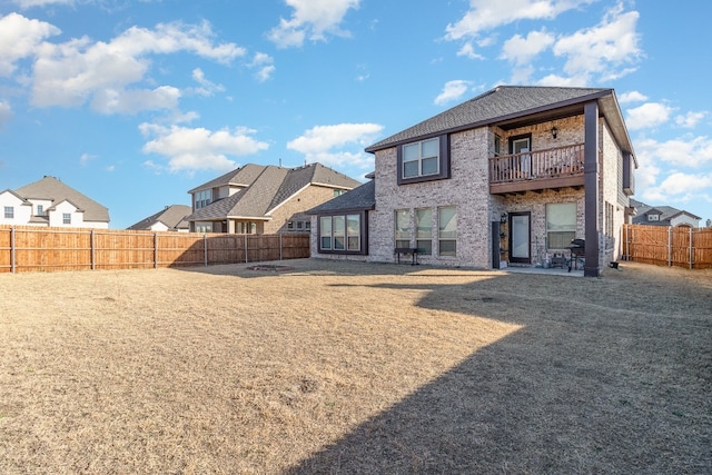 rear view of house featuring a balcony, a yard, and a patio area