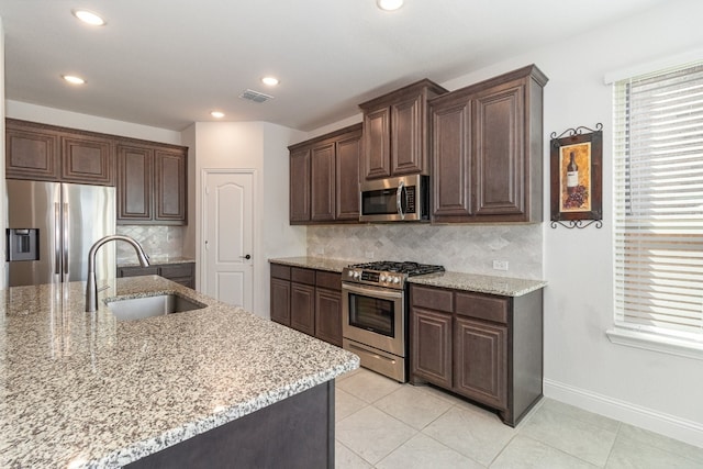 kitchen featuring sink, tasteful backsplash, stainless steel appliances, and light stone counters