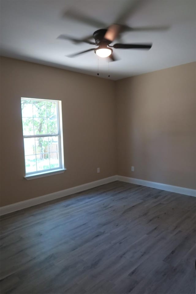 empty room with a ceiling fan, dark wood-style flooring, and baseboards