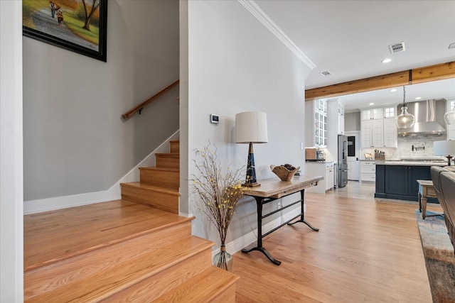 stairs with ornamental molding and hardwood / wood-style floors