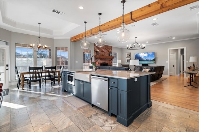 kitchen with a center island with sink, stainless steel dishwasher, sink, a fireplace, and decorative light fixtures