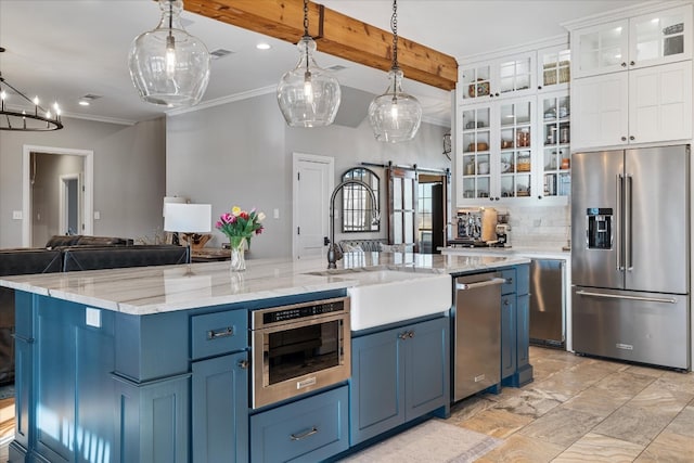 kitchen with a kitchen island with sink, white cabinetry, a barn door, and stainless steel appliances