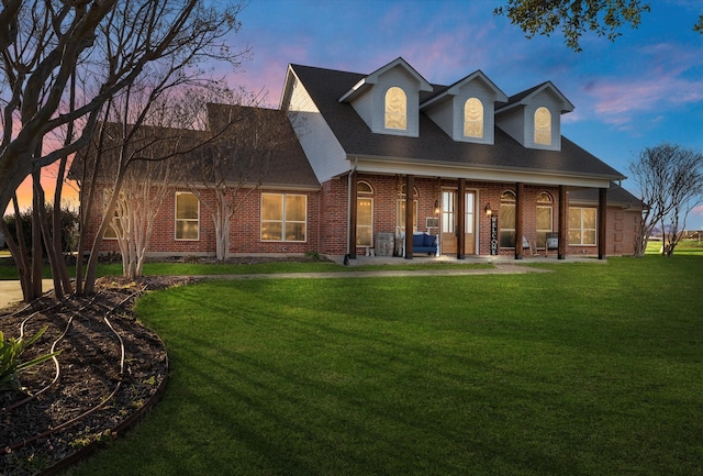 back house at dusk featuring a patio and a lawn