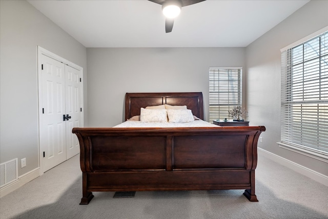 bedroom featuring light colored carpet, a closet, and ceiling fan