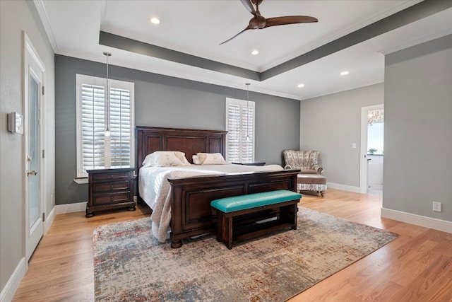 bedroom with light wood-type flooring, a raised ceiling, ceiling fan, connected bathroom, and ornamental molding