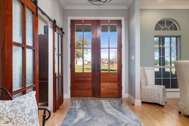 entryway featuring light hardwood / wood-style flooring, french doors, a barn door, and crown molding