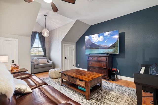 living room with ceiling fan, vaulted ceiling, and light wood-type flooring