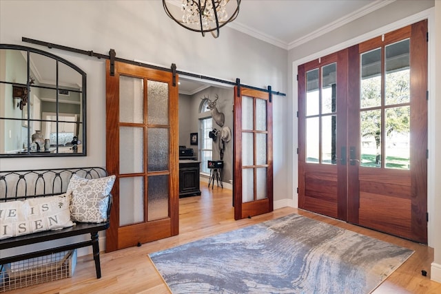 entryway featuring a barn door, a chandelier, wood-type flooring, crown molding, and french doors