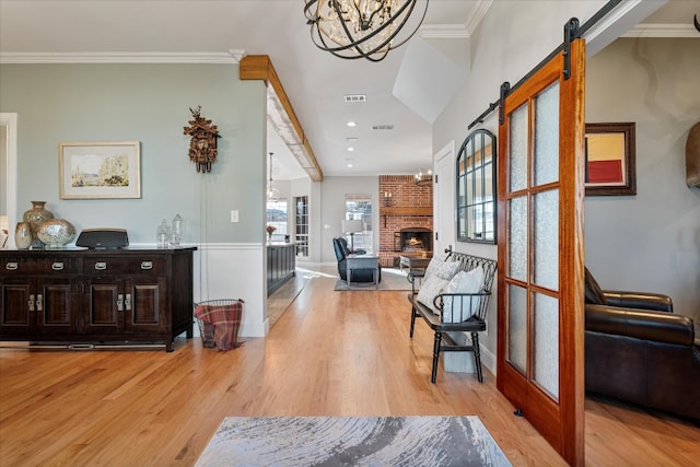 entryway featuring light hardwood / wood-style floors, ornamental molding, a barn door, and a fireplace