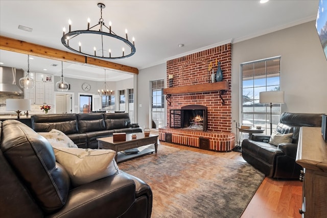 living room featuring beam ceiling, ornamental molding, light hardwood / wood-style flooring, and a brick fireplace