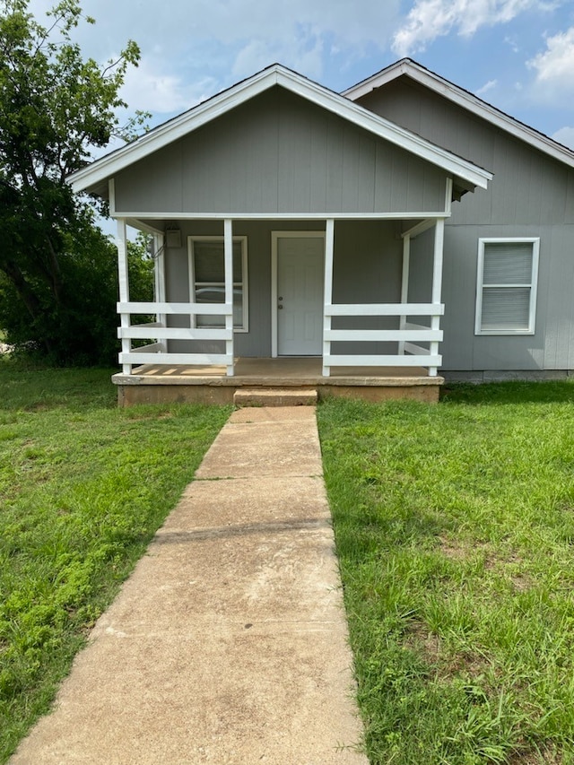 bungalow-style house featuring covered porch and a front yard