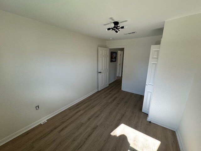 unfurnished room with ceiling fan and dark hardwood / wood-style flooring