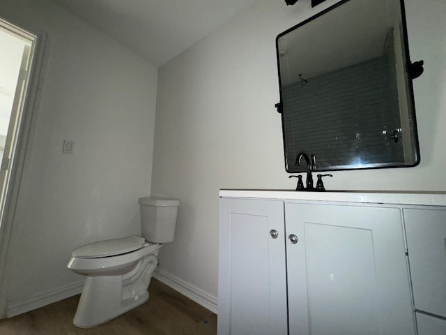 bathroom featuring toilet, vanity, vaulted ceiling, and wood-type flooring