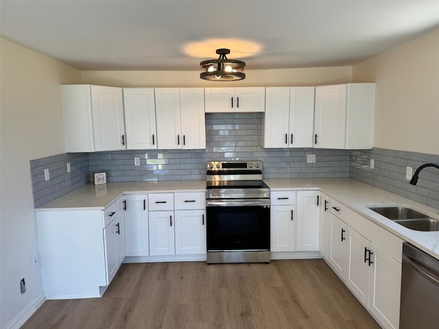 kitchen featuring stainless steel appliances, white cabinets, sink, and light wood-type flooring