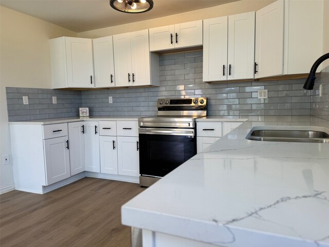 kitchen featuring stainless steel electric stove, tasteful backsplash, dark wood-type flooring, and white cabinetry