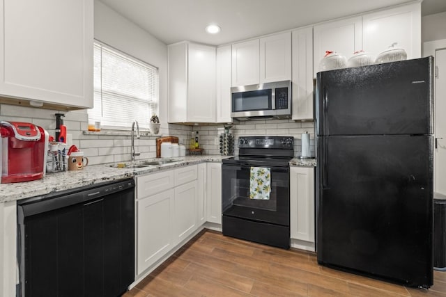 kitchen featuring sink, black appliances, tasteful backsplash, white cabinetry, and light wood-type flooring