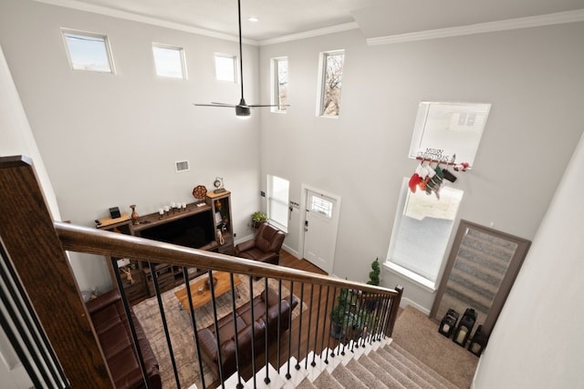 stairway featuring ceiling fan, a wealth of natural light, and ornamental molding