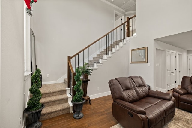 living room featuring crown molding, a high ceiling, and hardwood / wood-style flooring