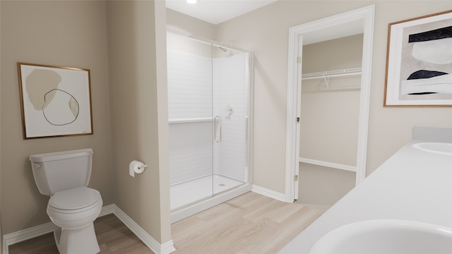 bathroom with a shower with shower door, toilet, wood-type flooring, and double sink