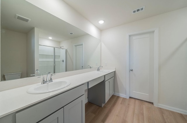 bathroom with vanity, hardwood / wood-style flooring, a shower with door, and toilet