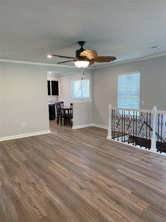 unfurnished room featuring crown molding, visible vents, a ceiling fan, wood finished floors, and baseboards