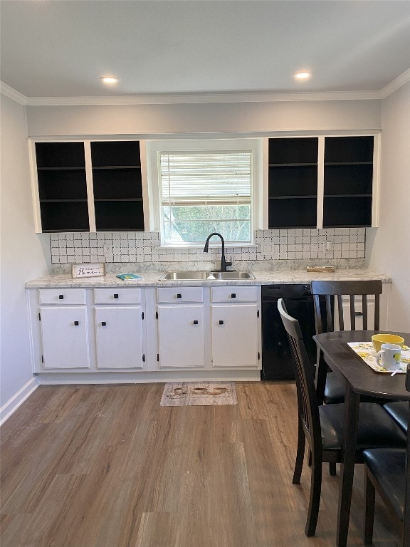 kitchen featuring light wood finished floors, tasteful backsplash, white cabinets, a sink, and dishwasher