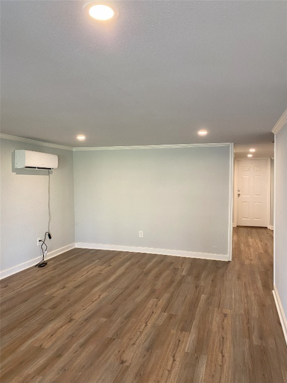 finished basement featuring dark wood-style floors, recessed lighting, ornamental molding, an AC wall unit, and baseboards