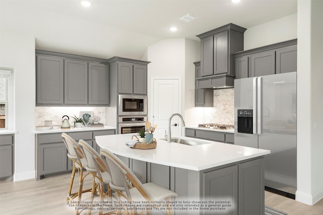 kitchen with gray cabinets, sink, lofted ceiling, and stainless steel appliances