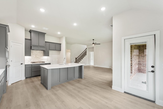 kitchen featuring a center island with sink, light hardwood / wood-style floors, gray cabinetry, and stainless steel gas cooktop