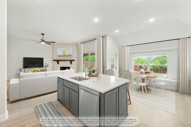 kitchen featuring gray cabinetry, ceiling fan, sink, dishwasher, and an island with sink