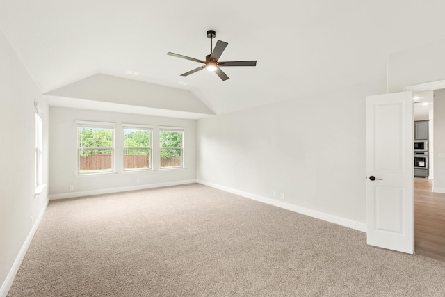 carpeted spare room with vaulted ceiling and ceiling fan