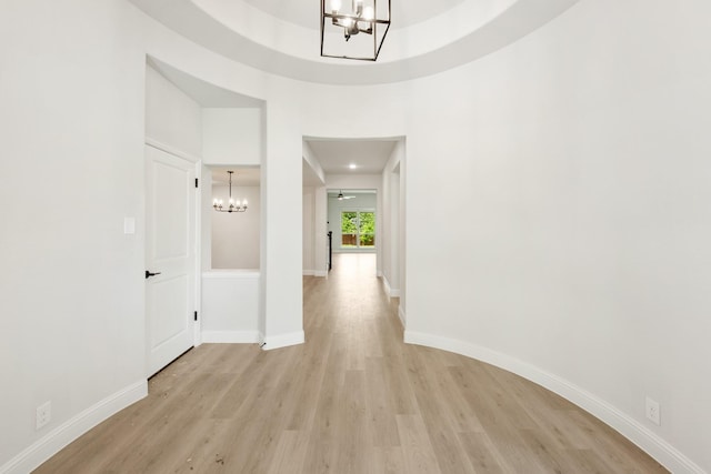 corridor with a notable chandelier and light wood-type flooring