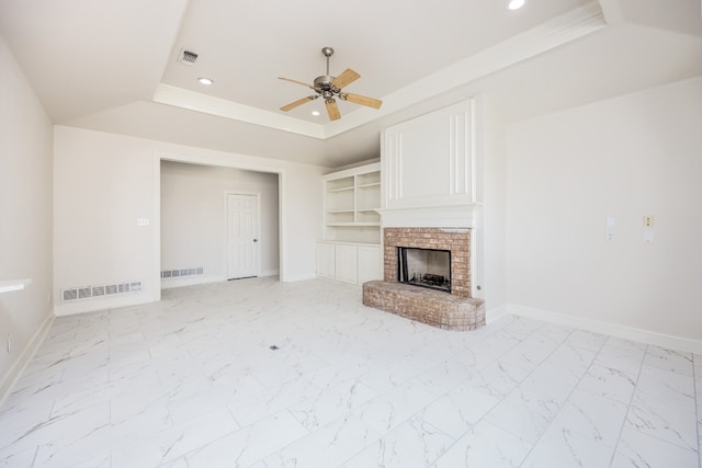 unfurnished living room featuring light tile floors, a brick fireplace, ceiling fan, a raised ceiling, and built in features