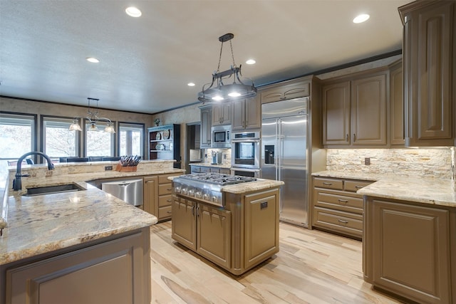 kitchen with a center island, built in appliances, light stone countertops, and decorative light fixtures