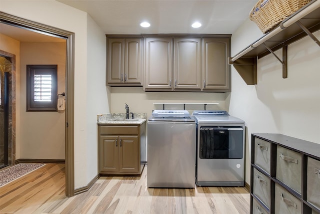 washroom with cabinets, sink, light hardwood / wood-style flooring, and washer and clothes dryer