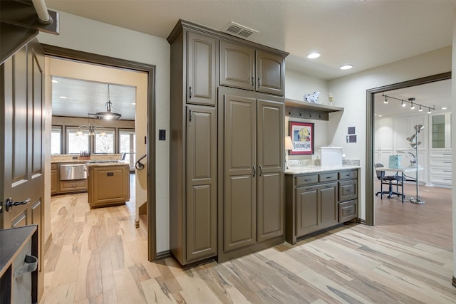 kitchen with light hardwood / wood-style floors, light stone counters, and rail lighting