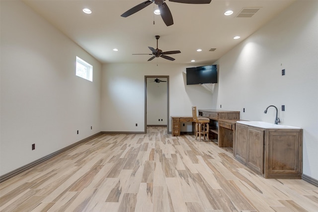 unfurnished living room with light hardwood / wood-style floors, sink, and ceiling fan