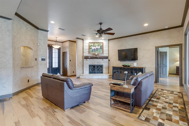 living room featuring a fireplace, crown molding, ceiling fan, and light hardwood / wood-style floors