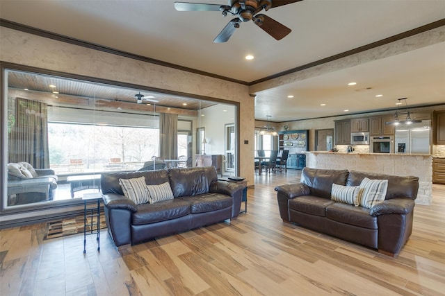 living room with light hardwood / wood-style floors, ceiling fan, and crown molding