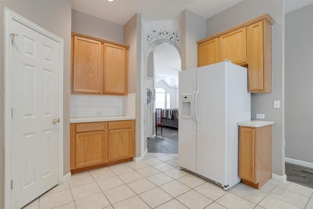 kitchen with light tile floors, backsplash, and white refrigerator with ice dispenser