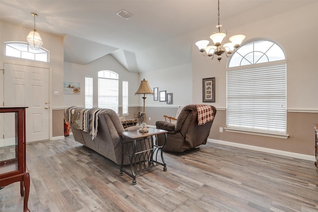 living room with plenty of natural light, hardwood / wood-style floors, lofted ceiling, and a chandelier