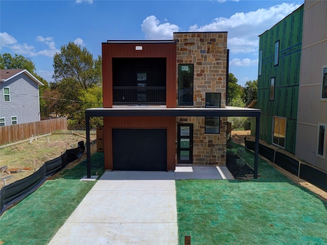 contemporary house featuring a front yard, a balcony, and a garage