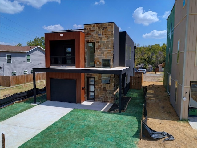 contemporary house with a balcony, a front yard, and a garage