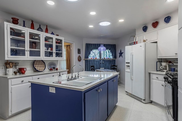 kitchen with a kitchen island with sink, white refrigerator with ice dispenser, sink, and pendant lighting