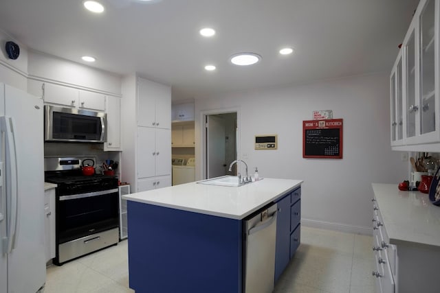 kitchen featuring an island with sink, blue cabinetry, white cabinetry, appliances with stainless steel finishes, and sink