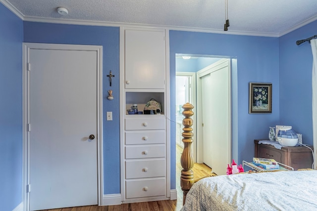 bedroom featuring ornamental molding, a textured ceiling, and light hardwood / wood-style flooring